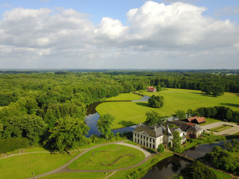 Luftaufnahme einer luxuriösen Glamping-Unterkunft mit Fluss, Wiesen, Feldern und viel Natur.