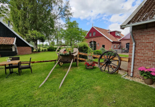 Gemütliche Glamping-Unterkunft mit altem Karren, bunten Blumen und ländlichem Bauernhofpanorama.