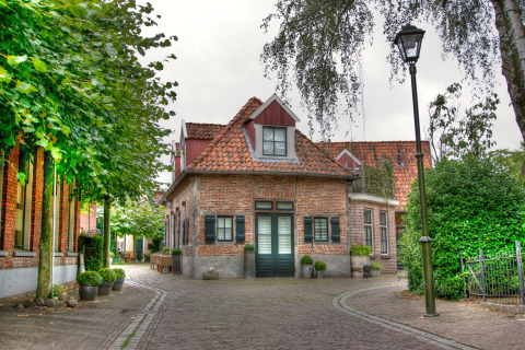 Charming glamping accommodation in a quaint village with cobblestone streets, greenery, and rustic buildings.