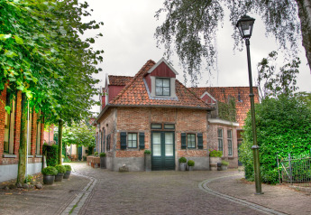 Charming glamping accommodation in a quaint village with cobblestone streets, greenery, and rustic buildings.