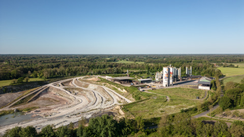 Luftaufnahme einer Glamping-Unterkunft mit Campingplatz, Industrieanlagen und grüner Landschaft.