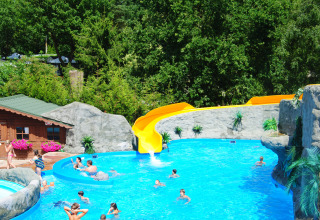 Außenpool mit gelber Rutsche und schwimmenden Menschen im Ferienpark Campingplatz Roland in Limburg.