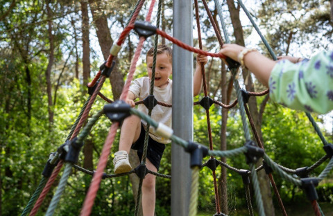 Un bambino scala una rete di corde al campeggio Roland, parco vacanze a Limburg, Paesi Bassi.