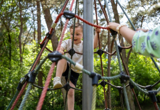 Un bambino scala una rete di corde al campeggio Roland, parco vacanze a Limburg, Paesi Bassi.