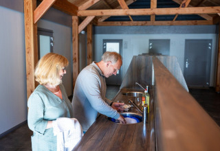 Elderly couple washing dishes together in a modern kitchen at Campsite Roland in Limburg, Netherlands.