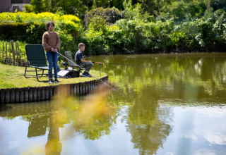 Due bambini pescano vicino a un lago al campeggio Roland, un parco vacanze in Limburg, Paesi Bassi.