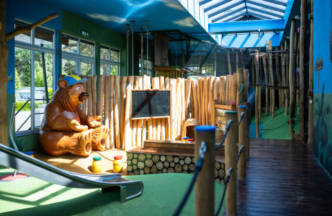 Indoor playground with bear statue and slide at Campsite Roland, a holiday park in Limburg, Netherlands.
