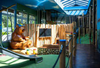 Area giochi interna con statua di orso e scivolo al Campeggio Roland, parco vacanze in Limburgo, Paesi Bassi.