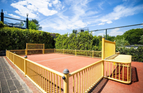 Small outdoor football pitch with yellow fencing at Campsite Roland in Limburg, Netherlands, on a sunny day.