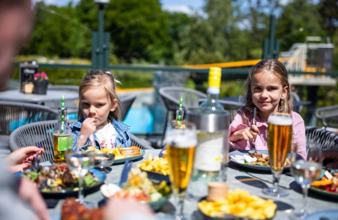 Two children enjoy an outdoor meal on a sunny day at Campsite Roland holiday park in Limburg, Netherlands.