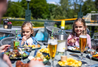 Two children enjoy an outdoor meal on a sunny day at Campsite Roland holiday park in Limburg, Netherlands.