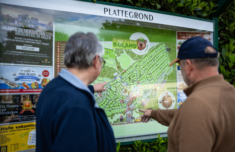 Due uomini guardano la mappa del Camping Roland su un pannello informativo nel Limburgo, Paesi Bassi.