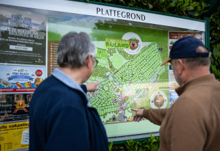 Due uomini guardano la mappa del Camping Roland su un pannello informativo nel Limburgo, Paesi Bassi.