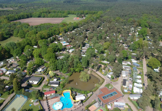 Aerial view of Campsite Roland holiday park in Limburg, Netherlands, showing pool, lake and forest.
