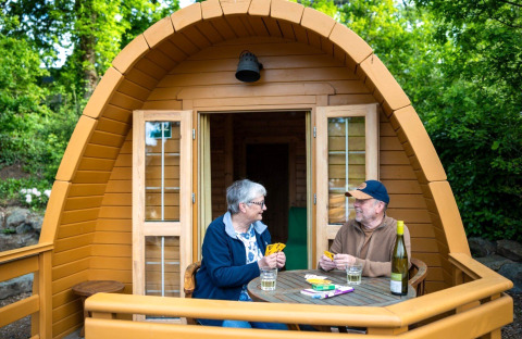 Zwei Personen spielen Karten auf der Terrasse einer Holz-Pod beim Campsite Roland in den Niederlanden.