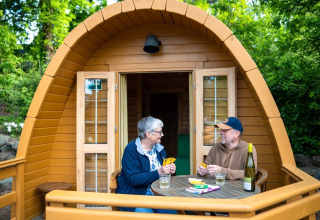 Zwei Personen spielen Karten auf der Terrasse einer Holz-Pod beim Campsite Roland in den Niederlanden.