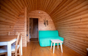 Holzinterieur eines Tiny House Pod auf dem Campingplatz Roland in den Niederlanden mit grüner Couch.