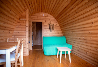 Holzinterieur eines Tiny House Pod auf dem Campingplatz Roland in den Niederlanden mit grüner Couch.