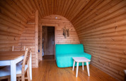 Wooden interior of a Pod tiny house at Campsite Roland in the Netherlands, featuring a green sofa.