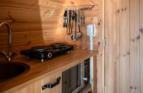 Kleine Küchenzeile im Pod am Campingplatz Roland, Niederlande, mit Herdplatte, Spüle und Mikrowelle.