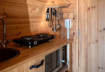 Coin cuisine du Pod au camping Roland, Pays-Bas, avec plaques électriques, évier et micro-ondes.