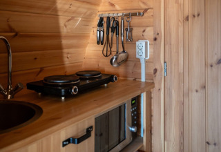 Compact kitchenette in the Pod at Campsite Roland, Netherlands, with hot plate, sink, and microwave.