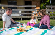 Familie macht Picknick auf einer Decke vor einem Safarizelt auf Campingplatz Roland in den Niederlanden.
