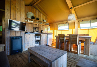 Interno di tenda safari al Campeggio Roland nei Paesi Bassi, con arredi rustici in legno e ambiente accogliente.