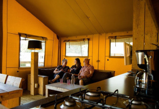 Interno della tenda safari al campeggio Roland nei Paesi Bassi con tre persone che si rilassano dentro.