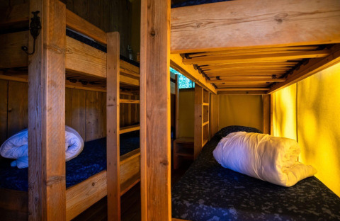 Interior of a safari tent with wooden bunk beds and rolled bedding at Campsite Roland, Netherlands.