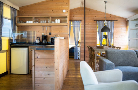 Innenansicht eines gemütlichen Safarizeltes mit Holzwänden, Küche, Esstisch und Sofa auf Camping Roland.