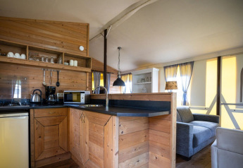 Vue intérieure d'une cuisine moderne et salon en bois dans une tente safari à colombages, aux Pays-Bas.