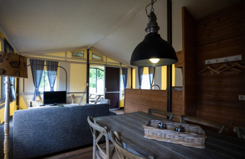 Interno di una tenda safari a struttura lignea al Campeggio Roland nei Paesi Bassi con zona soggiorno accogliente.