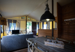 Innenraum eines Safari-Halbtimmerzelt auf Campingplatz Roland in den Niederlanden mit Ess- und Wohnbereich.