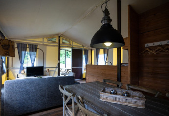 Interno di una tenda safari a struttura lignea al Campeggio Roland nei Paesi Bassi con zona soggiorno accogliente.