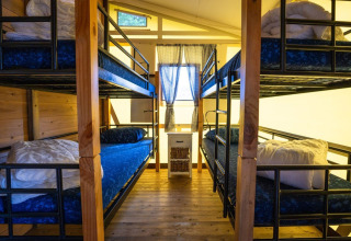 Innenraum eines Safarizelts mit zwei Etagenbetten und Holzboden auf dem Campingplatz Roland, Niederlande.