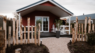 Extérieur du lodge Veluwe lounge + sauna avec allée gravillonnée, barrière en bois et terrasse confortable.