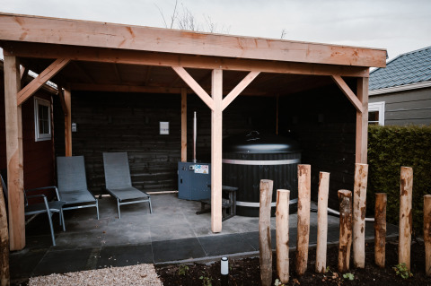 Área lounge exterior cubierta con tumbonas y sauna en Veluwe lounge + sauna en el parque De Boshoek, Países Bajos.