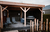 Área lounge exterior cubierta con tumbonas y sauna en Veluwe lounge + sauna en el parque De Boshoek, Países Bajos.