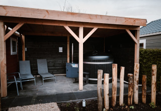 Überdachter Außenbereich mit Liegestühlen und Sauna in der Veluwe Lounge + Sauna, De Boshoek, Niederlande.