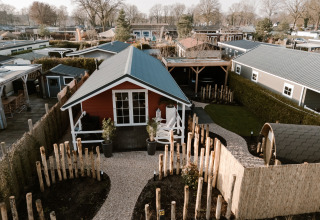 Lodge med sauna ved Recreation park De Boshoek i Holland, omgivet af hegn og grønne områder.