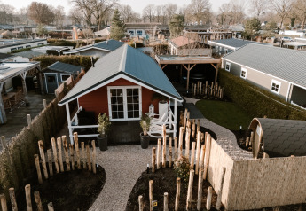 Lodge med sauna ved Recreation park De Boshoek i Holland, omgivet af hegn og grønne områder.