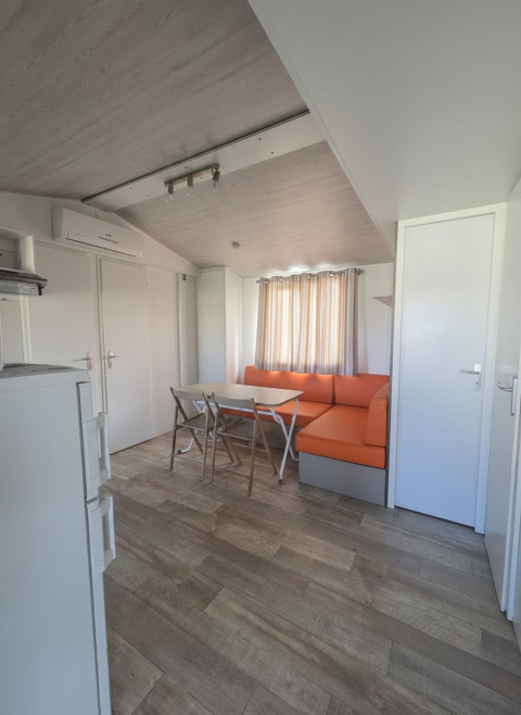 Indvendigt billede af et mobilhome 'Royal' på Centro Vacanze San Marino med orange sofa og spisebord.