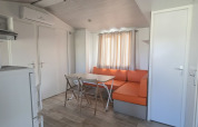 Vista interior de la casa móvil 'Royal' en Centro Vacanze San Marino, con sofá naranja y mesa comedor.