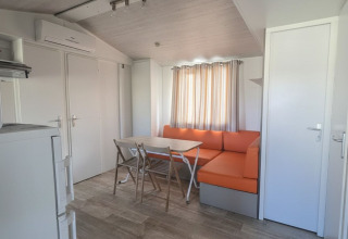 Vista interior de la casa móvil 'Royal' en Centro Vacanze San Marino, con sofá naranja y mesa comedor.