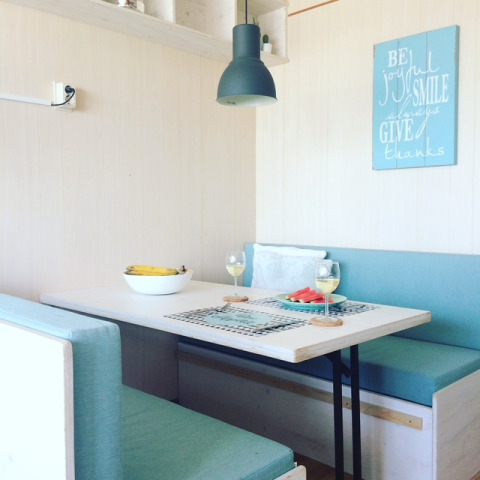 Coin repas lumineux dans la Beach sleeping cabin «Strand Dishoek 342» avec banquettes bleues et ambiance cosy.