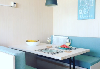 Helles Esszimmer in Beach sleeping cabin «Strand Dishoek 342» mit blauer Bank und moderner Lampe.