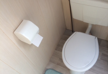 Modernes WC mit Klobrille, Papierrolle, hellblauem Teppich und zwei Kakteen im Beach sleeping cabin Strand Dishoek 342.