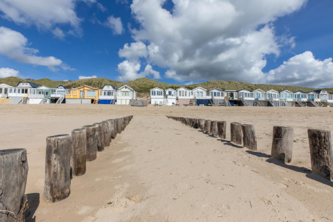 Cabines de plage alignées sur le sable avec des poteaux en bois à Dishoek, Zélande, Pays-Bas.