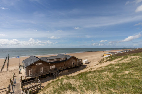 Udsigt over en strandhytte ved Strand Dishoek 342 i Zeeland, Holland, med klitter og hav i baggrunden.